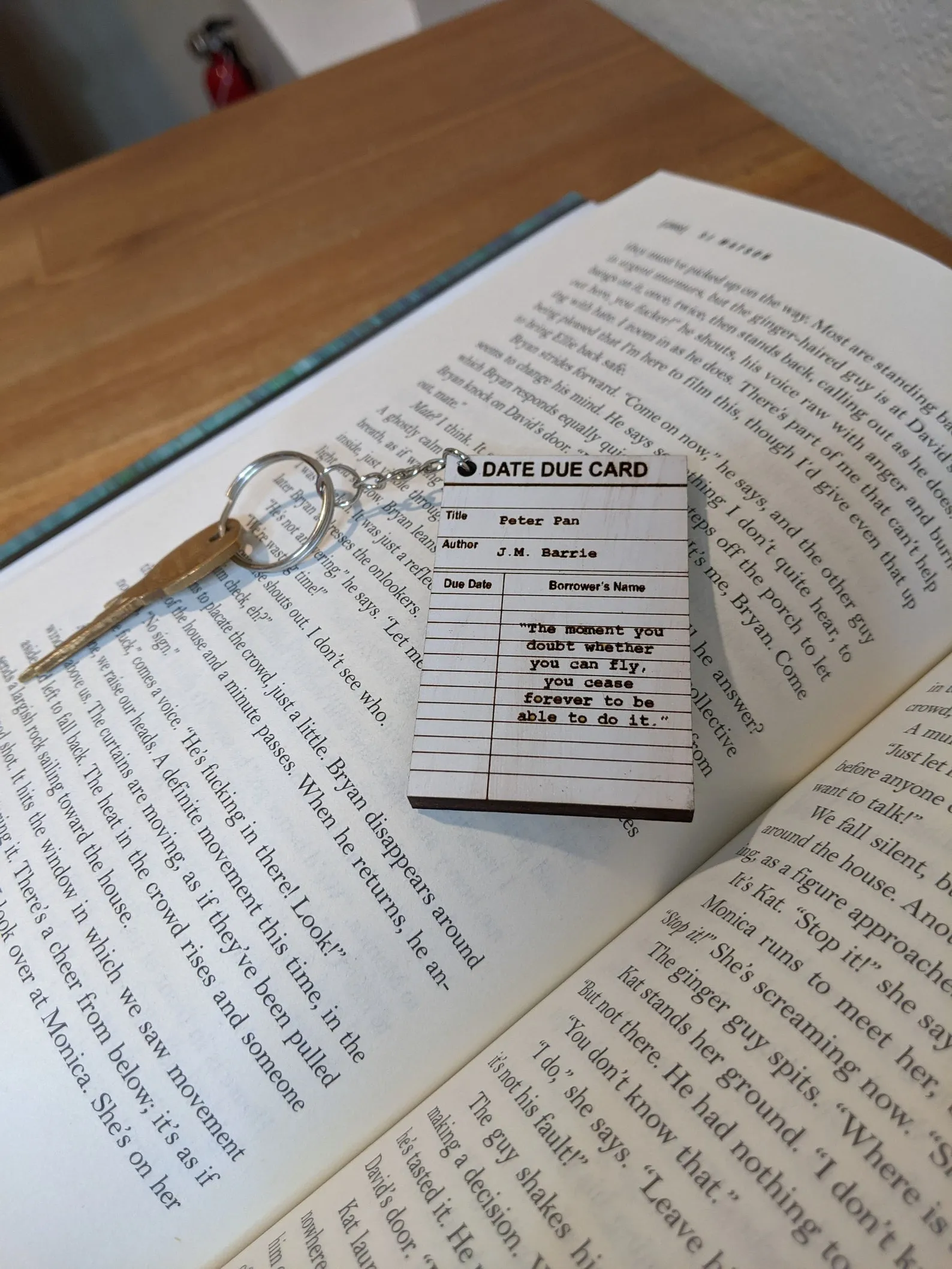 Image of a white due date card with a quote from Peter Pan. It's lying on an open book. 