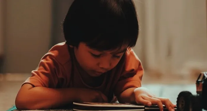 young kid laying on the floor reading