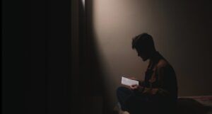 person reading on the edge of a bed