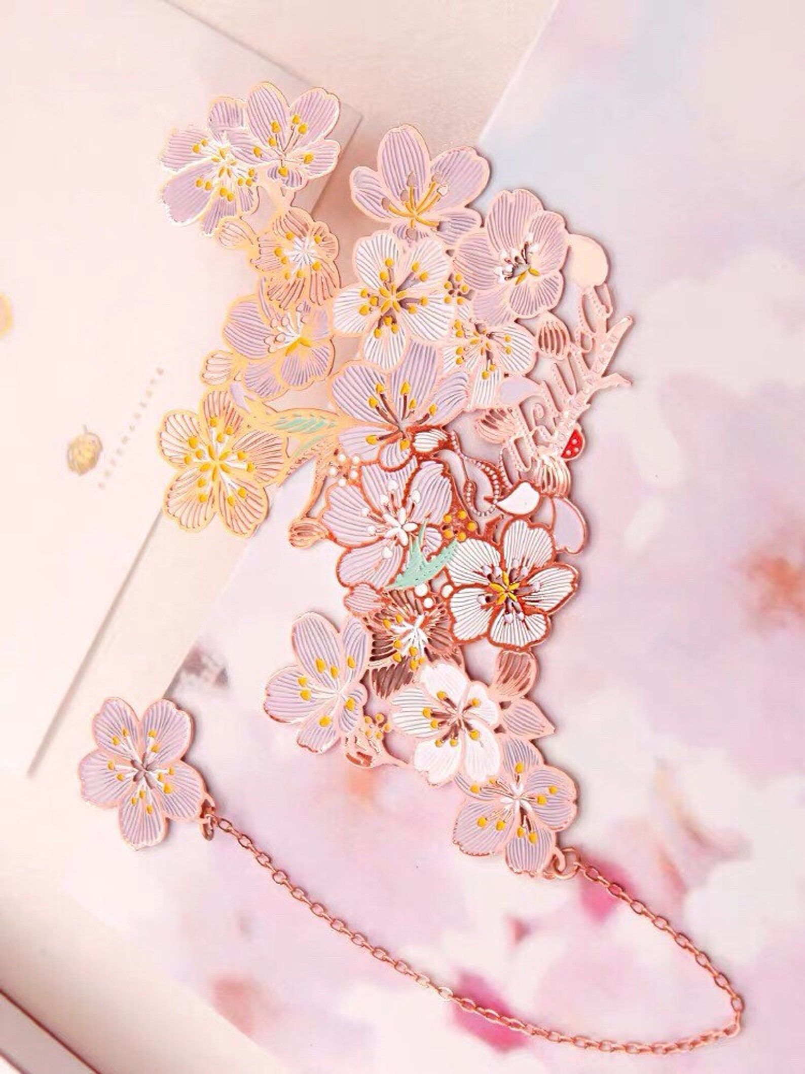 Image of an intricate rose gold plated sakura bookmrk.