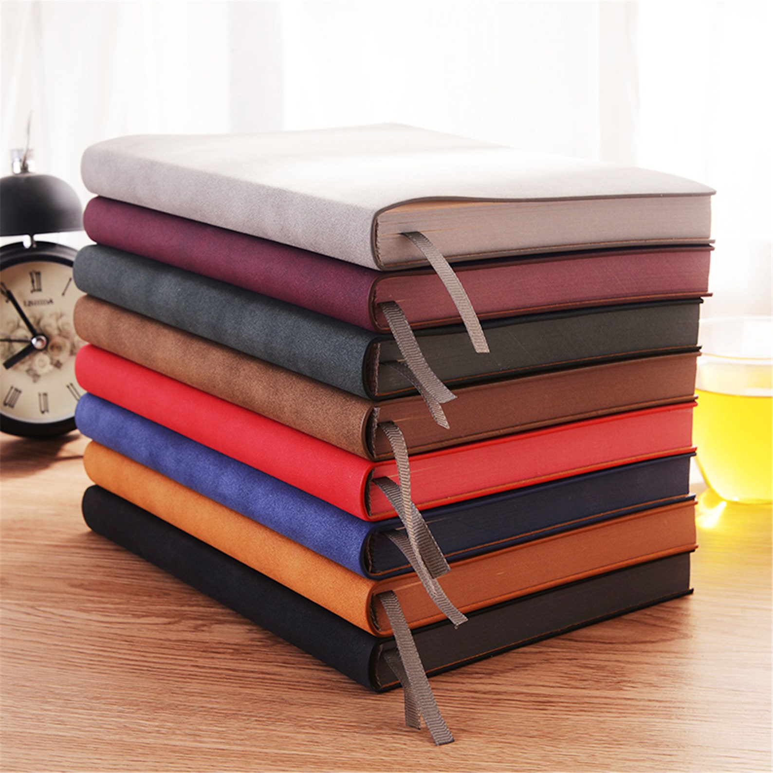 Image of a stack of notebooks in a range of colors. The page edges match the spin and cover colors. 