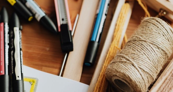 assorted writing utensils, twine, yarn, and measuring tools