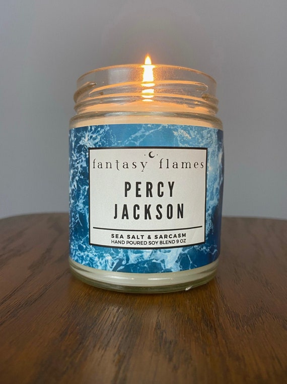 Photo of a lit Percy Jackson character scented candle - sea salt & sarcasm on a wooden tabletop
