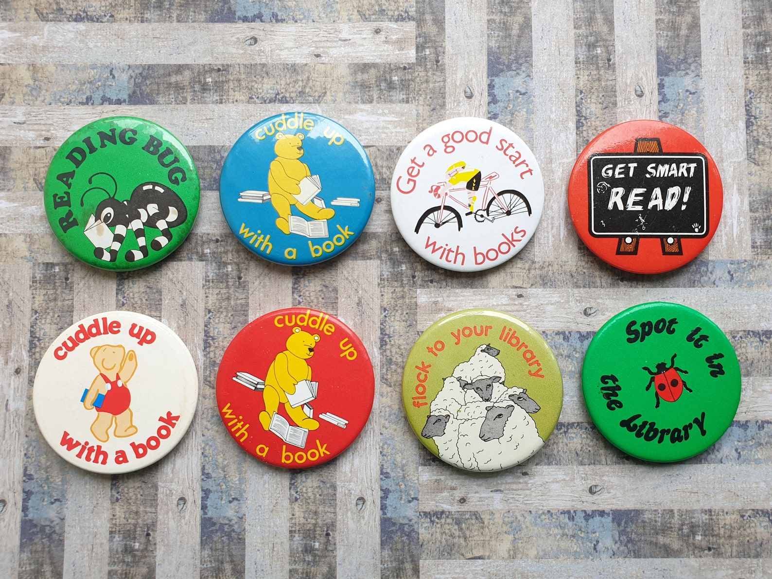 Image of eight pins featuring 80s images and font, all about the library and reading. 