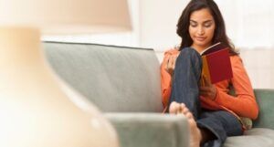 Image of brown woman reading on couch