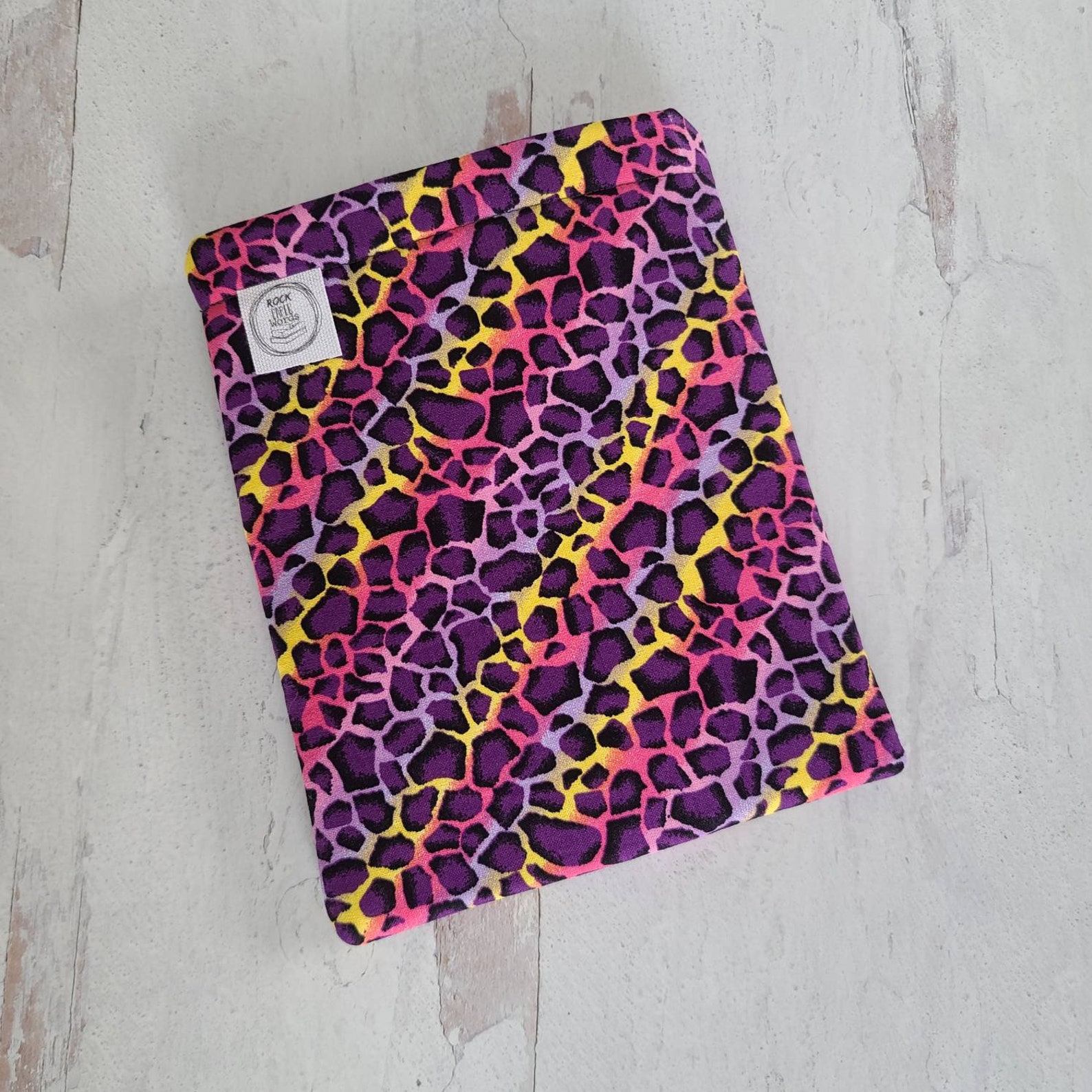 Image of a neon leopard print book sleeve on a gray background. 