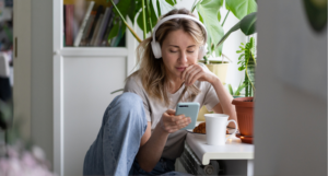 a photo of a person wearing headphones and looking at their phone in a coffee shop