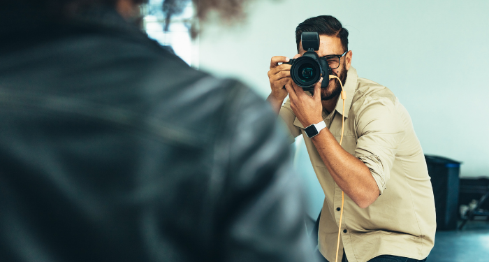 a photo of a photographer taking a picture of a person in the foreground