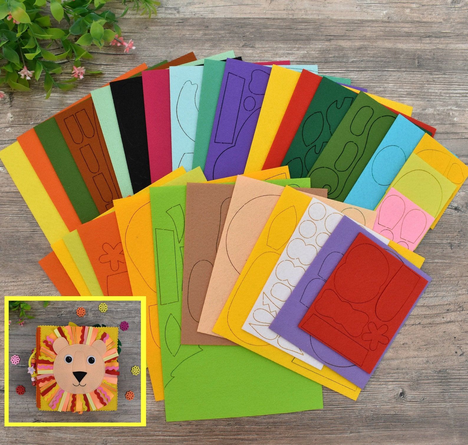 Colorful felt with black outlines in the background. The foreground image is of a quiet book with a lion on the front. 