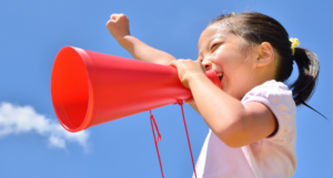 a photo of a Japanese girl yelling into a microphone and raising one fist