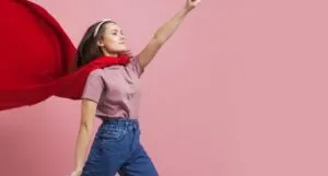 young, light-skinned woman in a red cape and jeans
