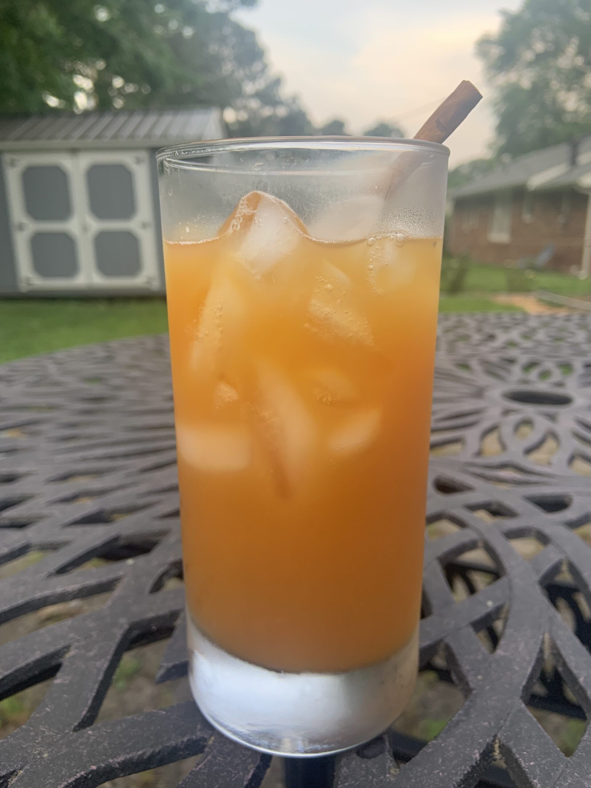 a photo of a glass of iced tea with orange juice and cinnamon stick