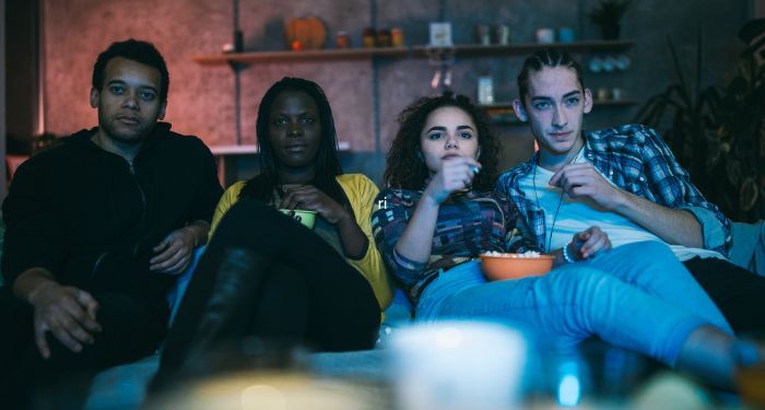 friends on a couch eating popcorn watching a movie