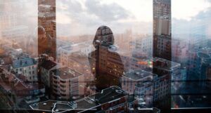 a douple-exposed photo showing a silhouette of a woman looking out onto a city from a window