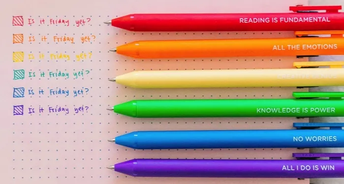 red, orange, yellow, green, blue, and purple pens overtop a notebook