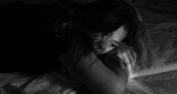 black and white image of girl laying down looking forlorn with long hair