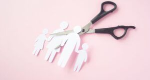 paper shaped into a family with a pair of scissors threatening to cut it up