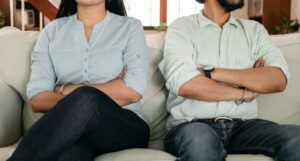 a couple on a sofa with their arms crossed looking away from each other