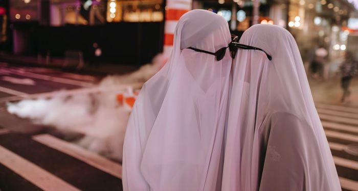 a couple in ghost costumes kissing on street