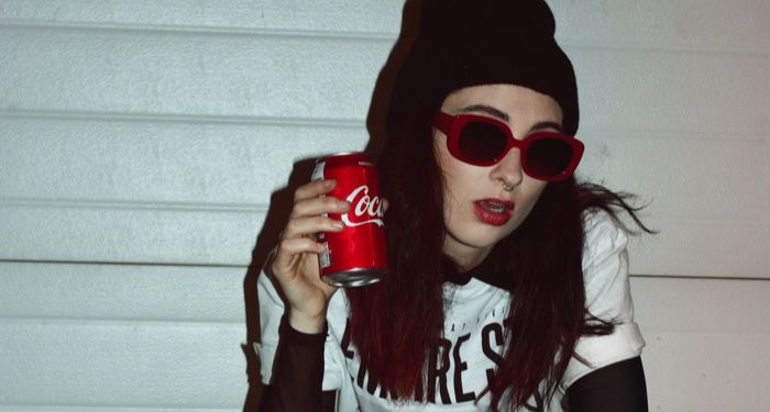 light-skinned girl with red lipstick, a beanie, holding a red can of coke