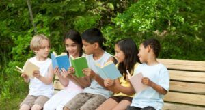 kids with skin tones ranging from light to tan sit on a bench with books