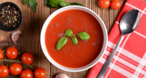 a photo of a bowl of tomato soup surrounded by baby tomatoes