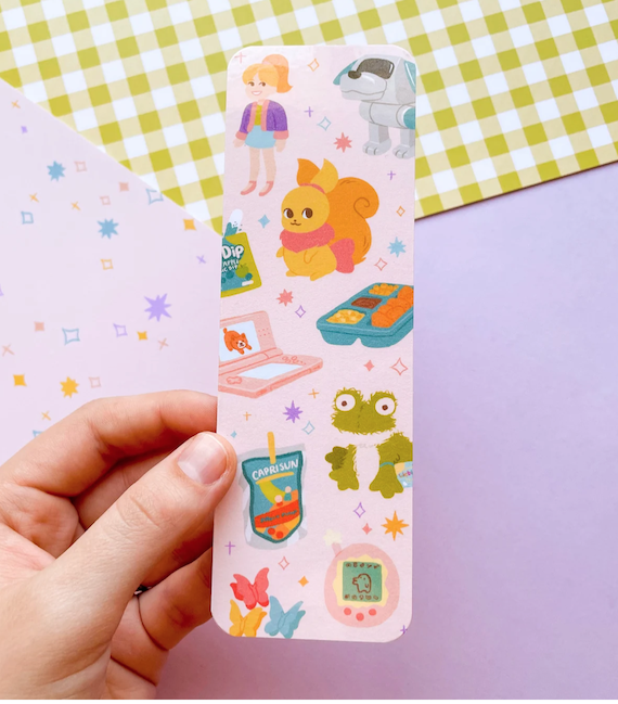 A bookmark that features many toys and snacks from the early 2000s including a Webkin, a Nintendo DS, and what appears to be a Neopet. 