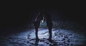 a couple kissing in the snow backlit by moonlight