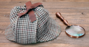 a photo of a magnifying glass and sherlock hat on a wood table