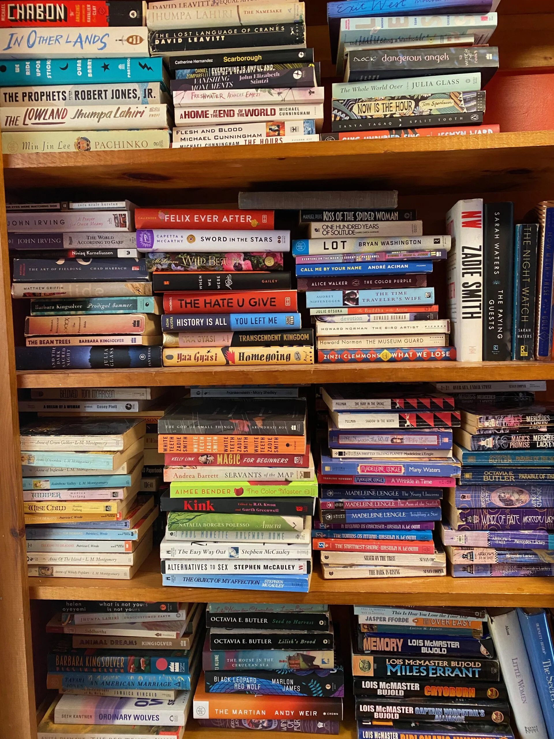 Close up of a tall bookshelf filled with many messy stacks of books. 