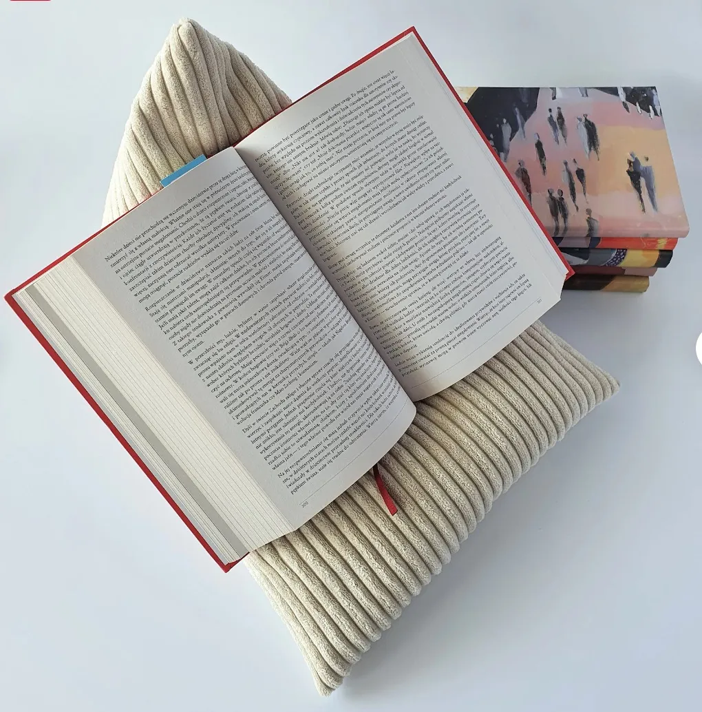 Image of a cream colored corduroy book pillow with an open book on top.