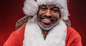 a photo of a smiling Black man with a short grey beard in a Santa outfit