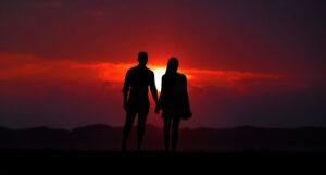a couple see in silhouette against a red sunset