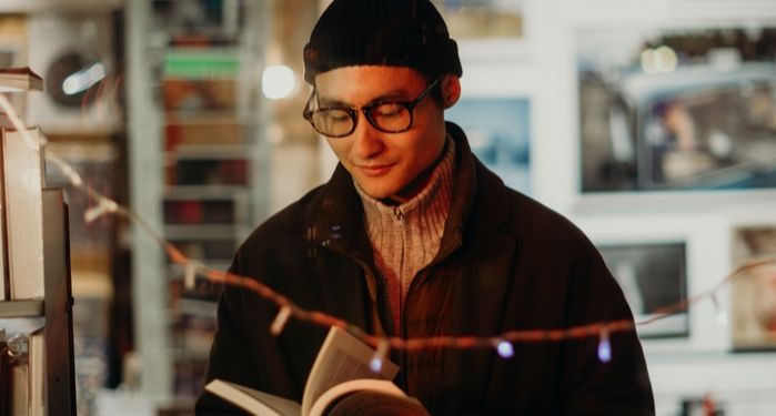 lightly tan-skinned man reading and smiling