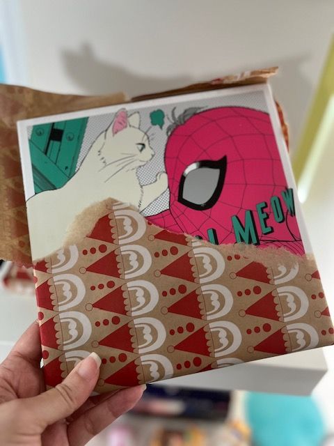 a hand holding a half unwrapped gift of Marvel Meow