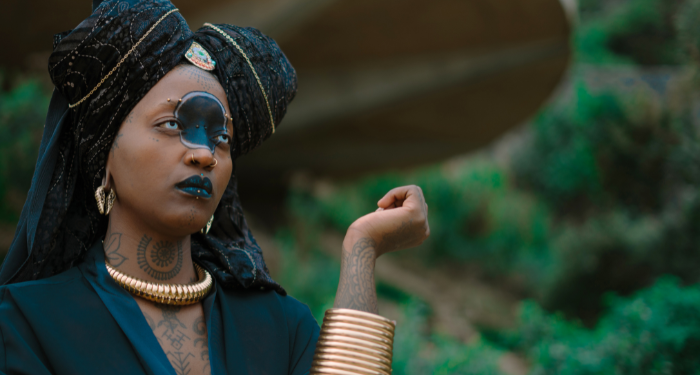 a photo of a Black woman with a circle painted on her face, wearing gold jewelry