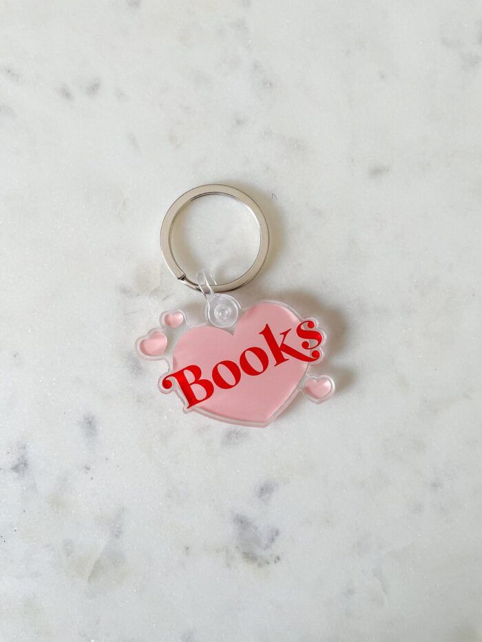 acyrlic keychain in the shape of a pink heart with the word "books" in red bubble fonf