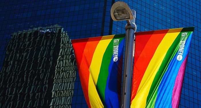 Image of City of Sydney rainbow Pride flags against a mirrored city building. Used with permission: https://www.flickr.com/photos/alexanderino/409358369/in/photostream/