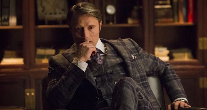 a still from Hannibal showing Mads Mikkelsen in front of bookshelves