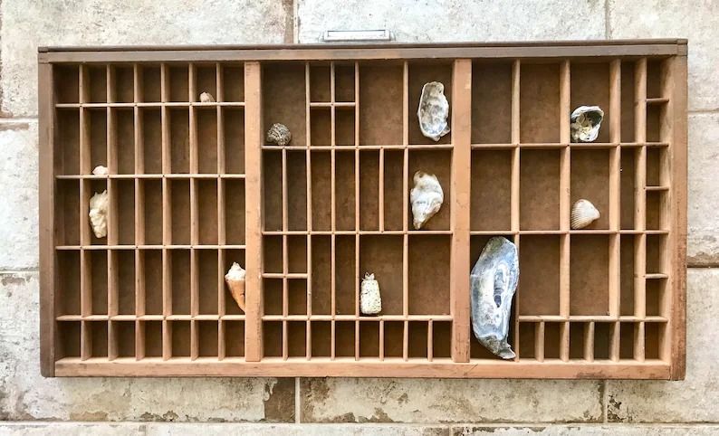 a photo of a wooden tray with small compartments, some filled with shells