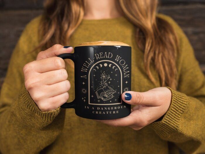 black mug with gold print reading "a well read woman is a dangerous creature."