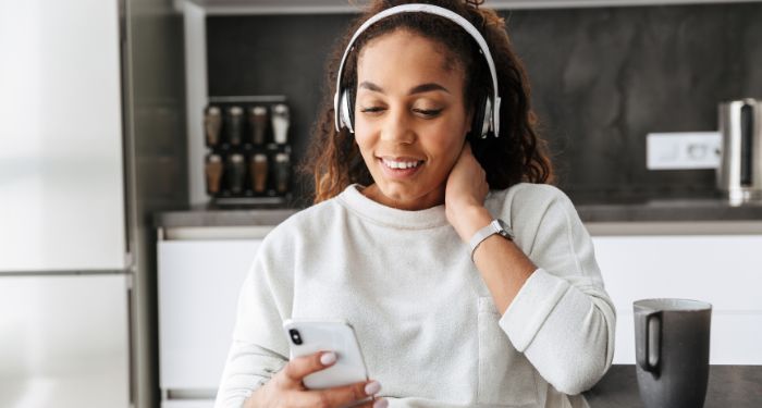 Black woman listening to something on her headphones and smiling in the kitchen