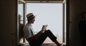 man in window frame reading a book