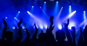 a photo of a musical performance with the audience's hands in the air