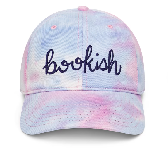 A purple and pink tie dye baseball cap with "bookish" embroidered in cursive