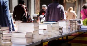 stacks on books arranged on several folding tables at a book fair