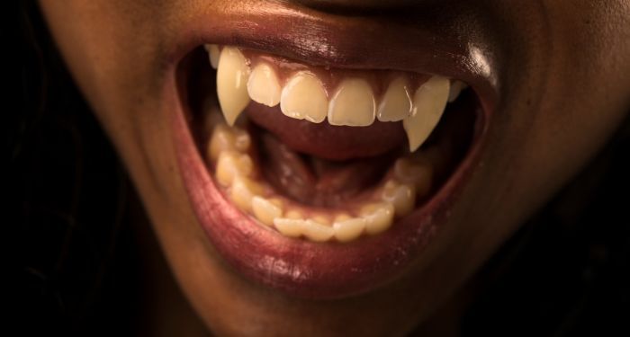 Close up image of a brown face with vampire teeth