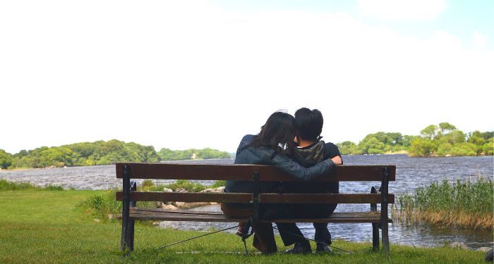 a couple embracing on a bench along a riverbank in Ireland