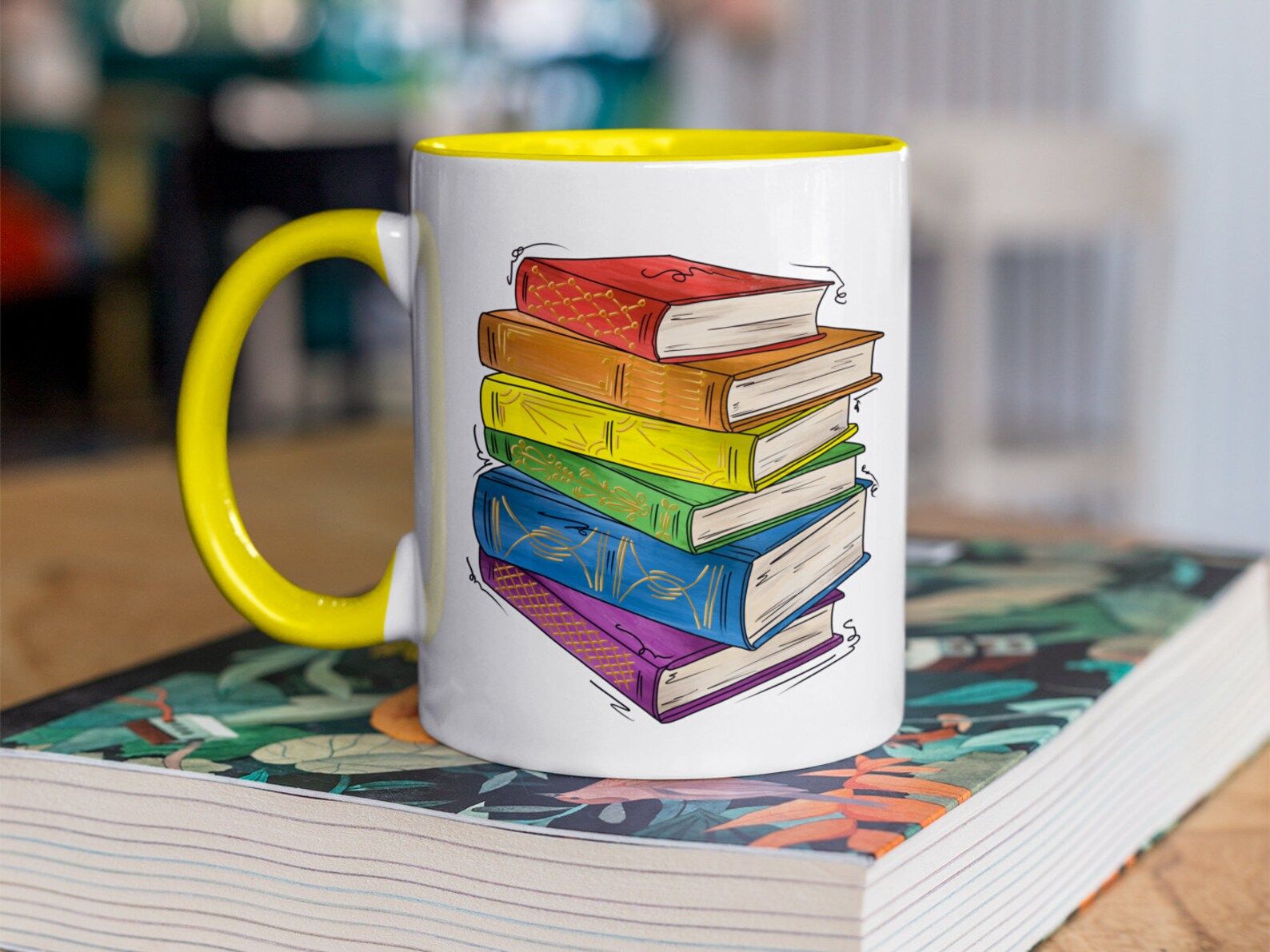 Image of a white mug with a rainbow book stack. 