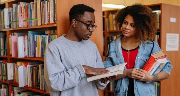 two Black people discussings books in a library